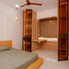 A modern minimalist bedroom at Mana Capitol, featuring a fluted glass wardrobe with integrated lighting and a compact study desk built into the unit.