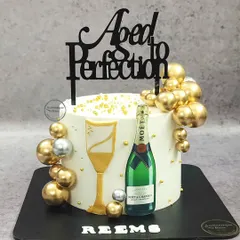 A Moët & Chandon champagne cake that's "Aged to Perfection." This celebratory cake is decorated with an edible champagne bottle, a glass, and shimmering gold bubbles.