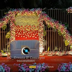 A unique Mehendi stage design with a curved structure covered in dense floral arrangements. The mix of red, white, and yellow flowers creates a vibrant and festive look.