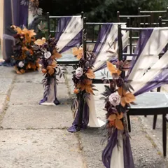 For a wedding ceremony, even the smallest details matter. I adorned these guest chairs with flowing purple and white fabric and floral accents to match the main wedding arch, ensuring a cohesive and beautiful look.