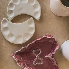 Imperfections add character. Here, a student's leaf-shaped dish and moon-phase palettes celebrate the beauty of the handmade.