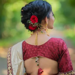 A beautiful, clean bridal bun with fresh red roses, showcasing a timeless and elegant hairstyle perfect for a Nauvari saree.