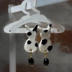 A pair of handmade ceramic earrings shaped like spotted bunnies, complete with black bead drops. This is an example of the wearable art from my 'Paw-try' collection.