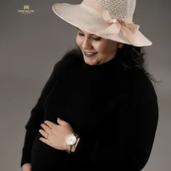A classic, elegant studio portrait of a mother-to-be. The simple black turtleneck and stylish hat create a timeless look that focuses all the attention on her happy glow and the baby bump.