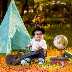 A whimsical outdoor setup for a little explorer. With a teepee, globe, and guitar, this baby boy looks like a tiny world traveler ready for his next adventure.