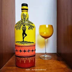A decorative bottle painted with a yoga tree-pose silhouette against a bright yellow background. The base features traditional patterns and mirror work, blending modern themes with folk art.