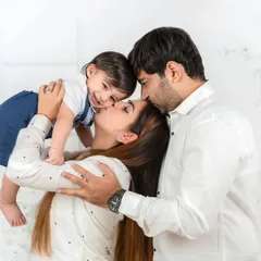 A tender, candid moment capturing the pure love of a family. A mother and father gently kiss their baby, creating a memory of warmth and connection that will last forever.