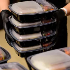 We ensure hygiene and convenience with our individually packed corporate meal boxes. Each meal is carefully prepared and sealed, making it a perfect solution for daily office lunches. This image shows our team handling a stack of meals ready for delivery.