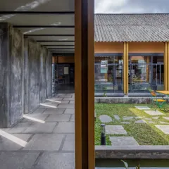 The building's structure is framed with ISMB sections, allowing for large, open spaces and expansive views of the courtyard and landscape. The walls are made of ferrocement finished with microconcrete.