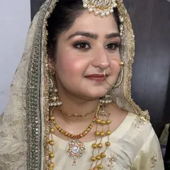 A detailed close-up of our elegant bridal makeup. This look features soft, blended eyeshadow, precise eyeliner, and a natural blush, all designed to enhance her features while complementing the intricate gold jewelry and attire.
