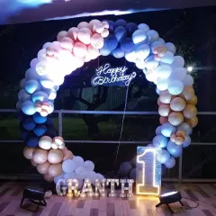 This modern and stylish first birthday decor shows how a circular frame and a sophisticated balloon color palette can elevate any home space. The setup includes marquee letters and a light-up number.