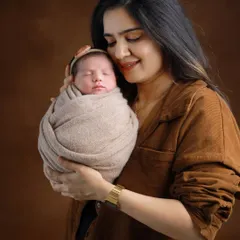A mother's gentle embrace. This portrait focuses on the tender bond between a mother and her newborn, set against a classic, warm brown backdrop for a timeless feel.
