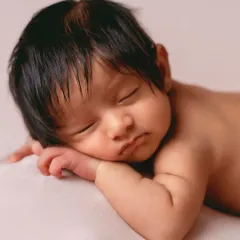The "tushy up" pose is a newborn photography classic. It shows off their sweet little back rolls and peaceful sleeping face on a simple, clean background.