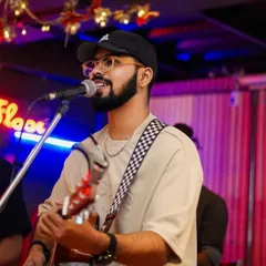 A candid shot from a performance at a cafe with neon lights. I adapt my style and energy to match the vibe of your venue, whether it's a chill evening or an upbeat night.