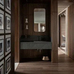 A powder room in the Pràna house, wrapped in vertical wood paneling. The fluted stone vanity and simple mirror create a look that is both modern and timelessly elegant.