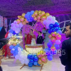 For a grand welcome baby celebration at a banquet hall, I created this large ring backdrop with blue, white, and gold balloons. The setup includes a 'Welcome Baby' neon sign and a central cake table, making it a stunning focal point for the event.
