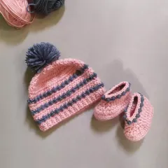 The Dewdrops beanie and booties set, shown together. The beanie features a fluffy pom-pom, and the booties have a matching design, creating a perfect gift set for a new baby.