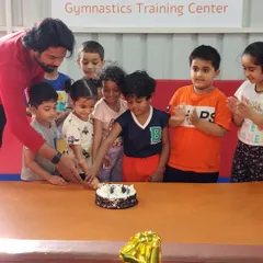 A coach helps our youngest members cut the anniversary cake. It's a joy to share these special moments with our gym family.