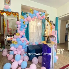 A cozy at-home baby shower with a beautiful arch of pink and blue balloons. The setup is designed to fit perfectly in a living room space, making it intimate and special.