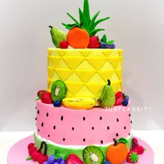 A "tutti frutti" two-tier cake, where the tiers themselves look like a pineapple and a watermelon. The cake is adorned with a variety of hand-molded, edible fruits.