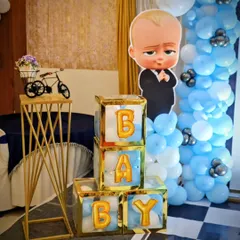 Fun props from the Boss Baby party, including a character cutout, 'BABY' blocks with gold balloon letters, and a decorative miniature bicycle.