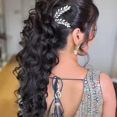 A chic and voluminous ponytail for a Sangeet night. The soft curls and elegant hair accessory create a look that is both modern and perfect for dancing the night away.