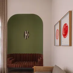 The home office at Rehethaan is bathed in morning sunlight. The space features a comfortable seating area with a sofa nestled in an olive-green archway, creating a perfect spot for breaks between work.