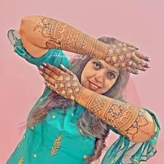 A happy bride posing with her full bridal mehendi. The design is intricate, and the stain is beautifully dark.