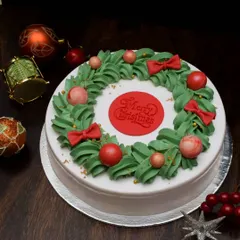 My festive Christmas wreath cake. This design features buttercream leaves piped into a wreath shape, decorated with red and pink fondant ornaments and bows.