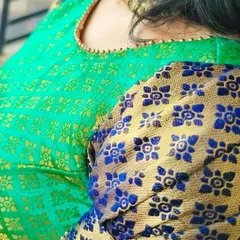 This detail shot shows the rich texture of the upcycled saree fabric used for the 'Neelam' dress. The puff sleeve combines a golden-hued base with a blue floral pattern, showcasing how we can blend different parts of a saree into a new, cohesive design.