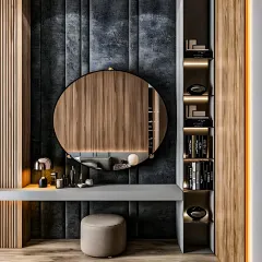 A modern and moody vanity area featuring a dark, textured wall panel and fluted wood accents. The large round mirror and floating grey countertop create a sleek and sophisticated look.