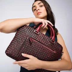 We used a clean white background for this Eske Global shot to draw all attention to the intricate woven texture of the maroon handbag. The model's direct gaze and confident hold present the bag as a statement piece.