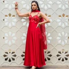 A full length shot showcasing a beautiful red anarkali. The makeup is kept classic with defined eyes and a matching red tone on the lips.