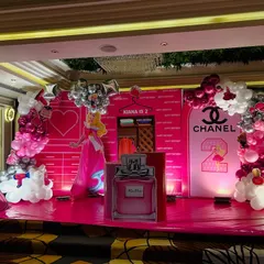 A closer look at the princess-themed stage, showcasing the detailed backdrop with a closet graphic, a large perfume bottle prop, and balloon garlands in shades of pink, white, and silver.