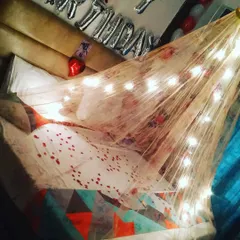 For a cozy and dreamy atmosphere, I create beautiful bed canopies using sheer fabric and warm fairy lights. This setup, complete with scattered petals, turns any bed into a romantic focal point for an anniversary or surprise.
