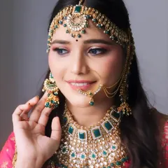 A radiant North Indian bride ready for her big day. This look features a heavy jewelry set paired with makeup that complements the outfit, focusing on glowing skin and defined features.