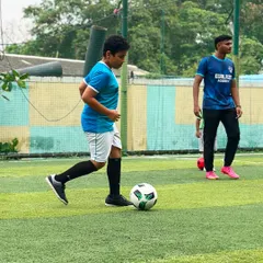 A young player focuses on his dribbling, with one of our coaches observing closely in the background to provide personalized feedback.