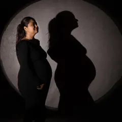A stunning play of light and shadow. This silhouette portrait and its shadow create a powerful, artistic image that celebrates the maternal form.
