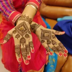 A modern and geometric take on the lotus motif. The flower is enclosed in a diamond shape with hanging jhumkas, creating a chic and symmetrical design on the back of the hands.