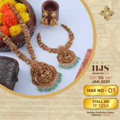 A complete temple jewellery set, featuring a long and short necklace with matching jhumkis. The design is centered around goddess motifs, accented with green beads, making it a classic and highly desirable bridal choice.