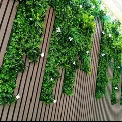 I can create custom patterns by combining different elements. This wall features dark vertical louvered panels with sections of artificial greenery, creating a modern, graphic design that adds both texture and a biophilic touch.