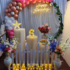 A beautiful ring arch decoration in shades of pink and rose gold. The setup is complete with a neon sign, illuminated marquee letters for the name, and floral arrangements for an elegant touch.