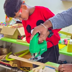 A student carefully guides a jigsaw to cut a piece of wood for his project. We prioritize one on one attention, especially when kids are learning to use power tools for the first time.
