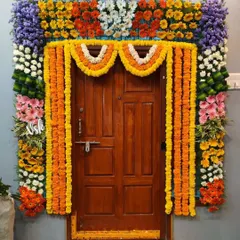 A dense and colorful floral frame for a home entrance. This decoration uses a variety of flowers like marigolds, lilies, and chrysanthemums to create a vibrant and celebratory welcome for guests.