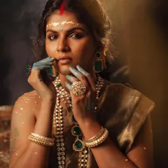 This pose highlights the statement rings and the contrast of the blue paint on the model's hands against the golden theme. Every detail in the styling adds to the narrative of strength.