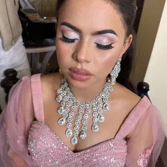 A close-up of a reception glam look. The focus is on the eyes, with a soft pink cut-crease and dramatic lashes, paired with a statement diamond necklace.