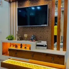 This TV unit design is all about luxury and function. It features a textured back panel, a white marble-finish console with open and closed storage, and a unique illuminated pebble tray at the bottom.