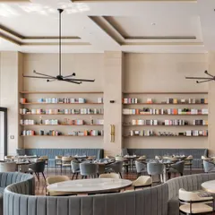 Curved, velvet-upholstered banquette seating at the Elevate Clubhouse. This furniture choice softens the geometry of the large space, creating more intimate pockets for dining and conversation within the open-plan restaurant.