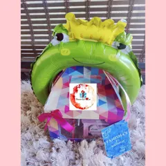 A creative return gift hamper for a kid's birthday, topped with a crowned frog prince balloon. I can create unique and fun favors in bulk for children's parties, making them a hit with young guests.