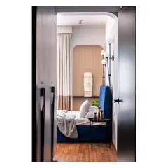 A view into another bedroom in the "Kanasu" project, where a deep blue bed is framed by an arched doorway. The design incorporates Moai-style sculptures, reflecting the client's enthusiasm for art.